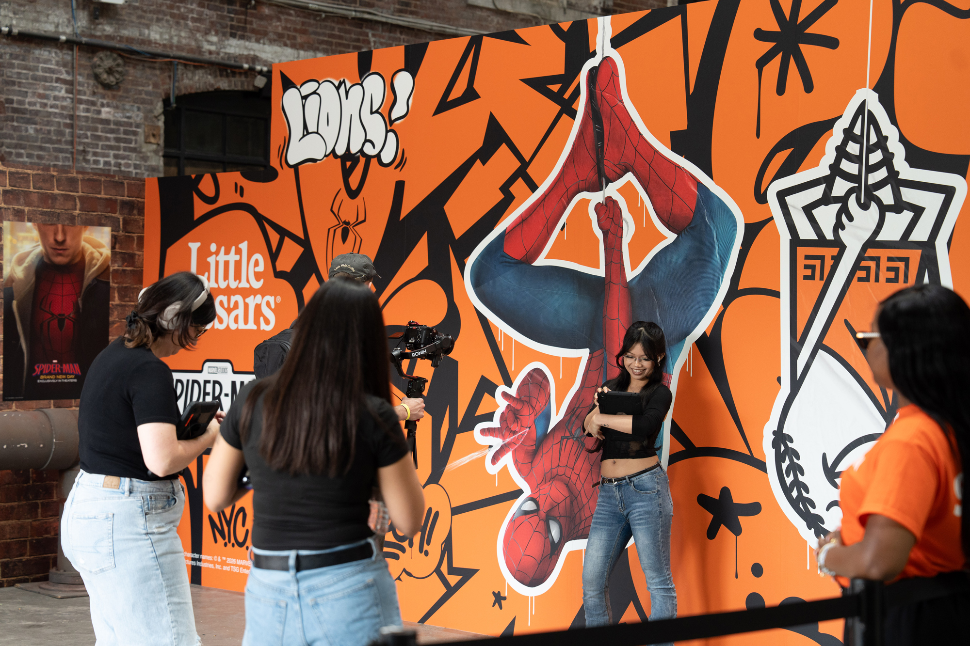 Fan taking a selfie in front of the hanging Spider-Man cutout on the container wall